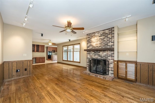 739 Muir View Dr, Ballwin, MO 63011 - unfurnished living room with rail lighting, a wainscoted wall, ceiling fan, wood finished floors, and wooden walls