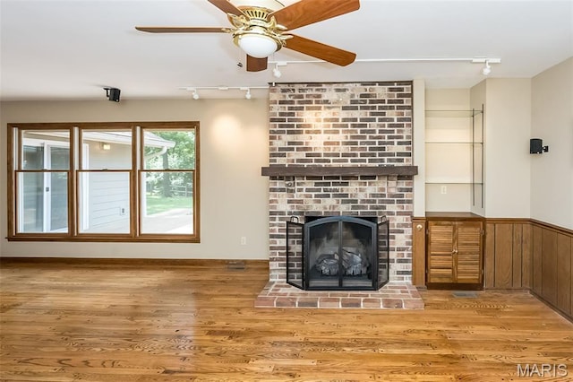 739 Muir View Dr, Ballwin, MO 63011 - unfurnished living room with track lighting, ceiling fan, wood finished floors, a brick fireplace, and wainscoting