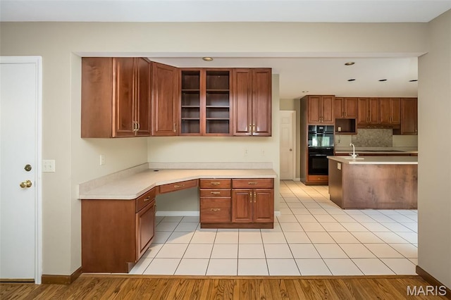 739 Muir View Dr, Ballwin, MO 63011 - kitchen featuring light countertops, glass insert cabinets, brown cabinetry, and baseboards