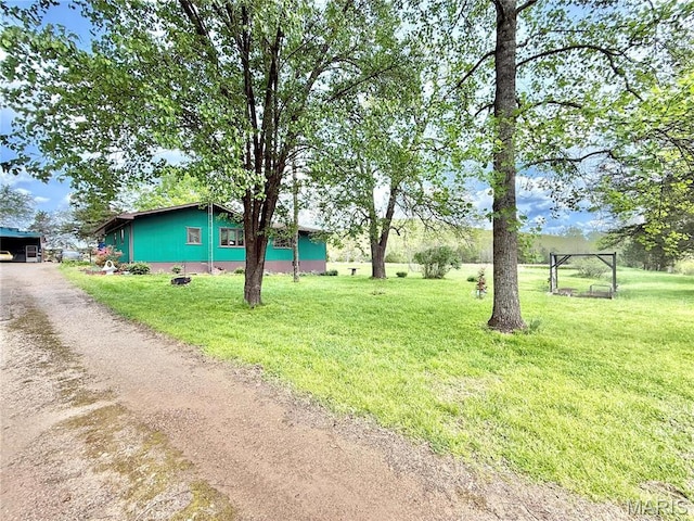 view of green lawn featuring dirt driveway