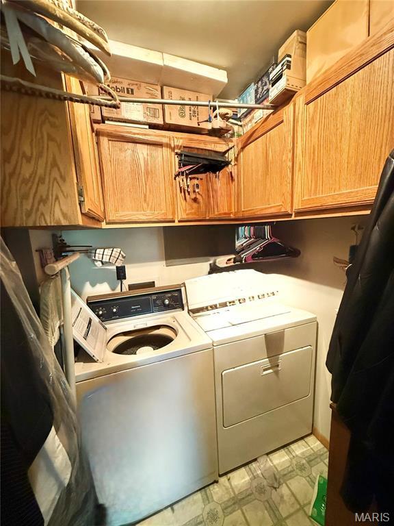 laundry area with cabinet space, washing machine and clothes dryer, and light floors