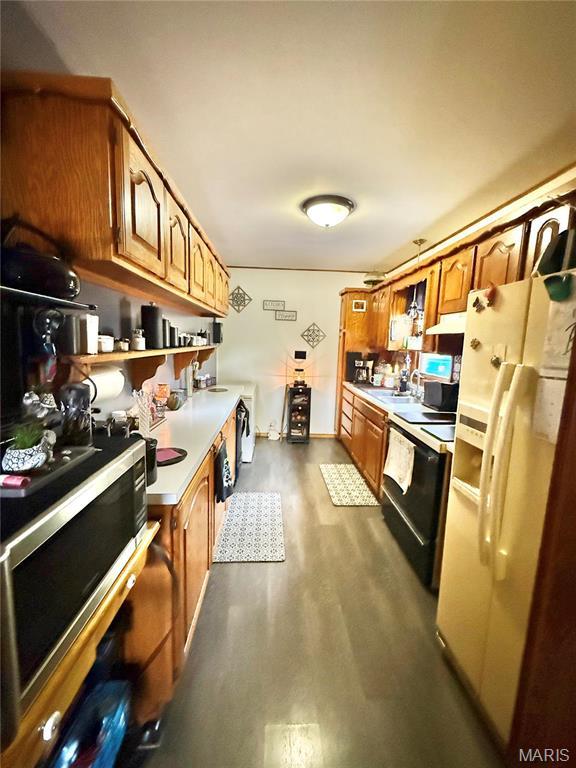 kitchen featuring white fridge with ice dispenser, electric range, light countertops, stainless steel microwave, and dark wood-type flooring