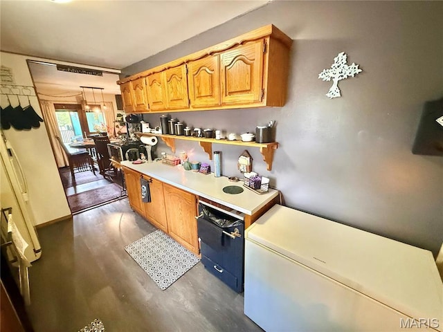 kitchen with light countertops, dark wood-style flooring, decorative light fixtures, and fridge