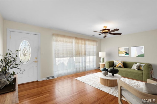 living area with a ceiling fan, wood finished floors, and baseboards