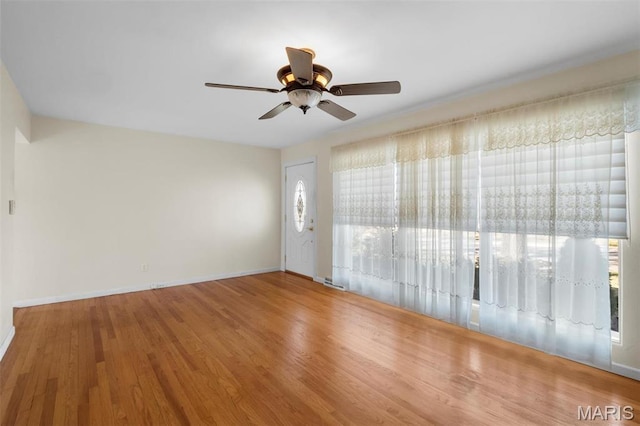 spare room featuring ceiling fan, baseboards, and wood finished floors