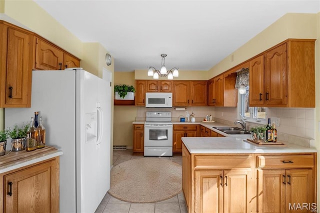 kitchen with white appliances, a sink, a chandelier, a peninsula, and light countertops