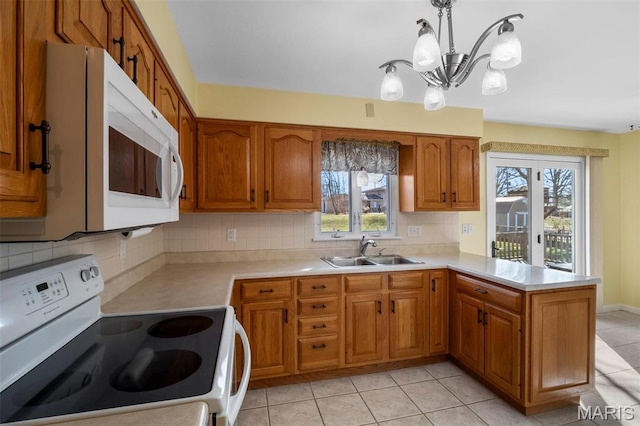 kitchen with white appliances, a sink, a chandelier, and brown cabinets