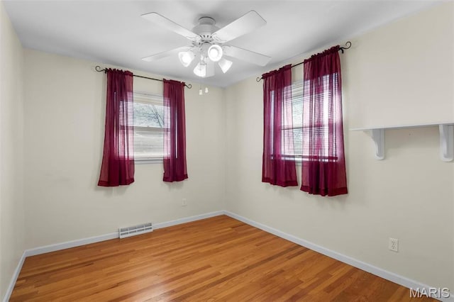 unfurnished room featuring baseboards, wood finished floors, and a ceiling fan