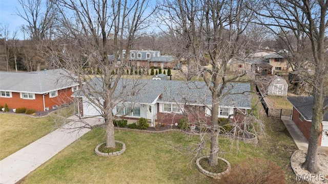 view of front of home with concrete driveway, a front yard, a residential view, and brick siding