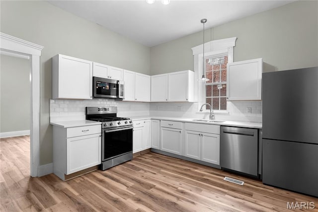 306 Walnut St, Waterloo, IL 62298 - kitchen with stainless steel appliances, a sink, light countertops, tasteful backsplash, and white cabinetry