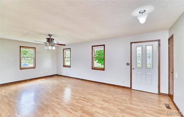 foyer entrance featuring light wood-style flooring, a textured ceiling, a ceiling fan, and baseboards
