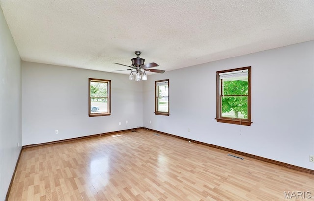 unfurnished room with a textured ceiling, light wood-style flooring, a ceiling fan, and baseboards