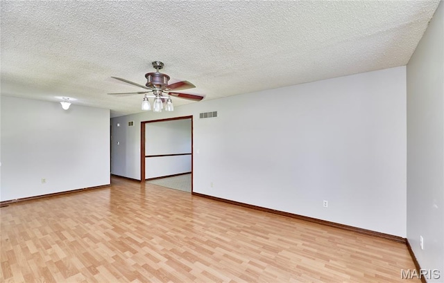 spare room featuring light wood-type flooring, ceiling fan, baseboards, and a textured ceiling