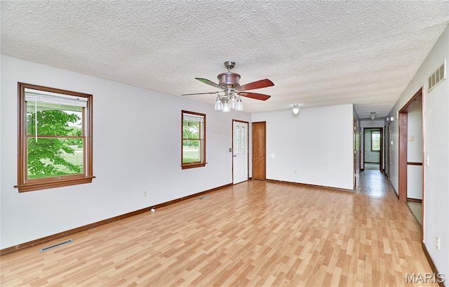 unfurnished room featuring light wood finished floors, ceiling fan, a textured ceiling, and baseboards