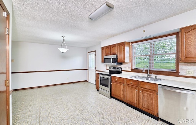 kitchen with stainless steel appliances, a sink, light countertops, healthy amount of natural light, and a textured ceiling