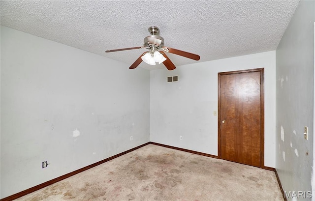 empty room featuring carpet flooring, a ceiling fan, baseboards, and a textured ceiling
