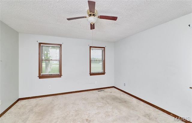 carpeted empty room with plenty of natural light, baseboards, a textured ceiling, and a ceiling fan