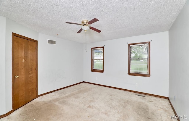 empty room with carpet flooring, ceiling fan, baseboards, and a textured ceiling