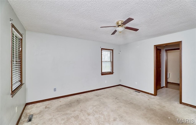 spare room featuring ceiling fan, carpet floors, baseboards, and a textured ceiling