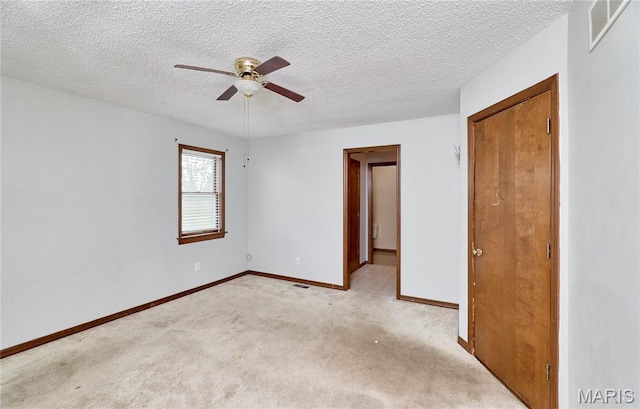 unfurnished bedroom featuring light carpet, baseboards, a textured ceiling, and a ceiling fan