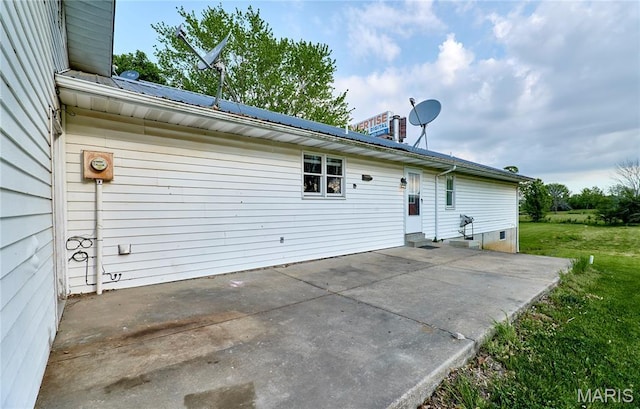 rear view of house featuring a patio, a lawn, and metal roof