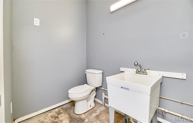 bathroom featuring toilet, unfinished concrete flooring, vanity, and baseboards