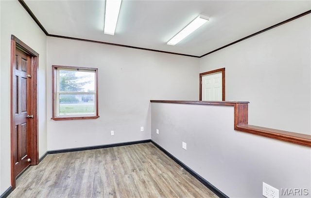 spare room with wood finished floors, ornamental molding, and baseboards
