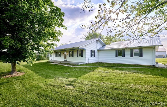 rear view of property with a lawn and metal roof
