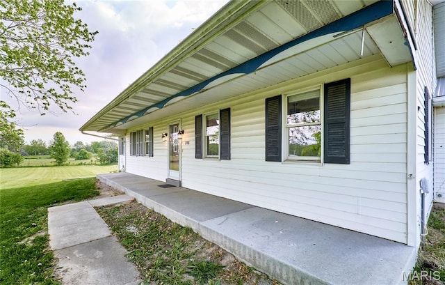 doorway to property featuring a porch and a yard