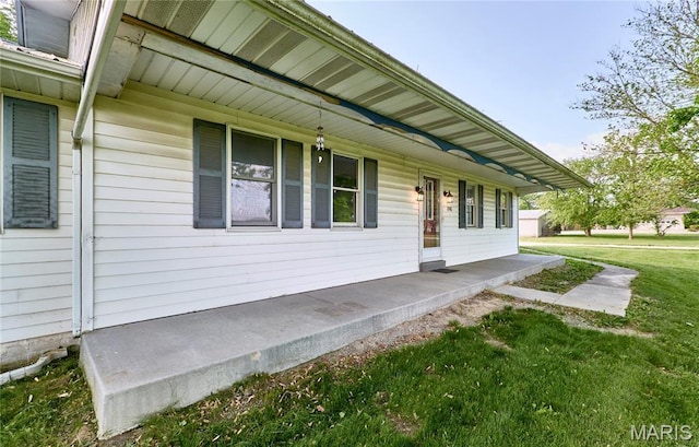 view of exterior entry with a porch and a lawn