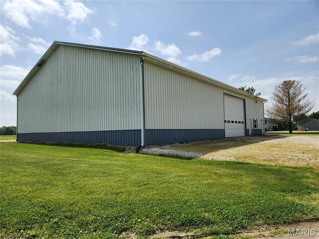 view of side of home with a lawn, an outdoor structure, a garage, and an outbuilding