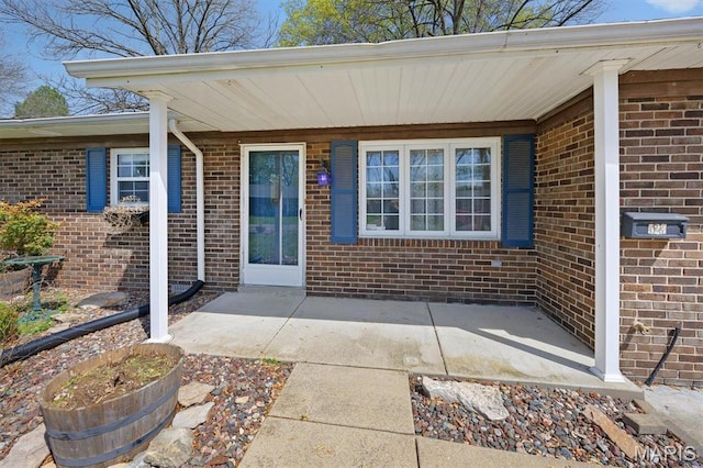 entrance to property with brick siding and a patio area