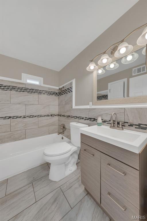 6635 Donald St, Saint Louis, MO 63121 - full bath featuring tile walls, toilet, vanity, and shower / bathtub combination