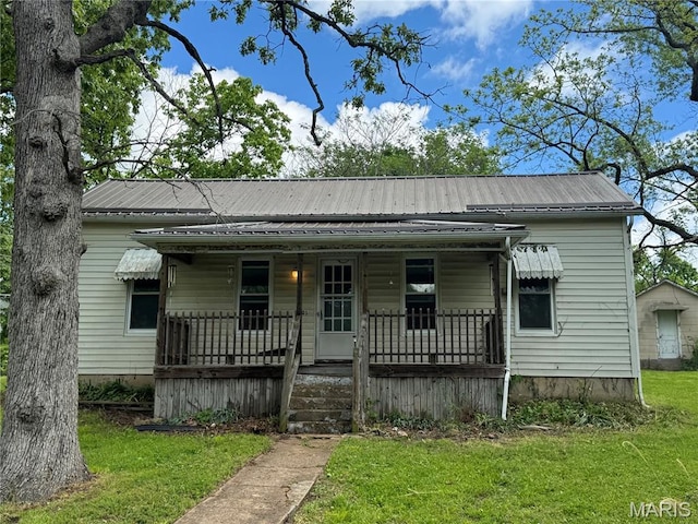 view of front of property featuring covered porch, a front yard, and metal roof