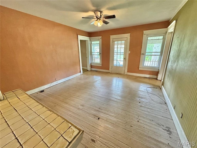 unfurnished room with light wood-style floors, ceiling fan, and baseboards