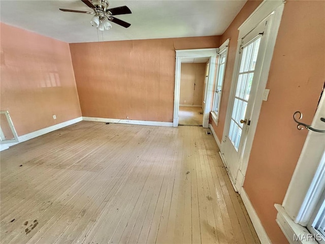 unfurnished room featuring hardwood / wood-style floors, a ceiling fan, and baseboards