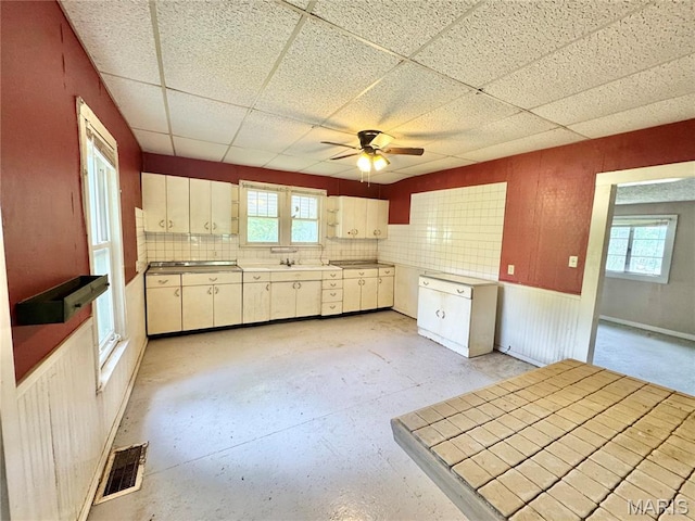 kitchen featuring healthy amount of natural light, ceiling fan, and a paneled ceiling