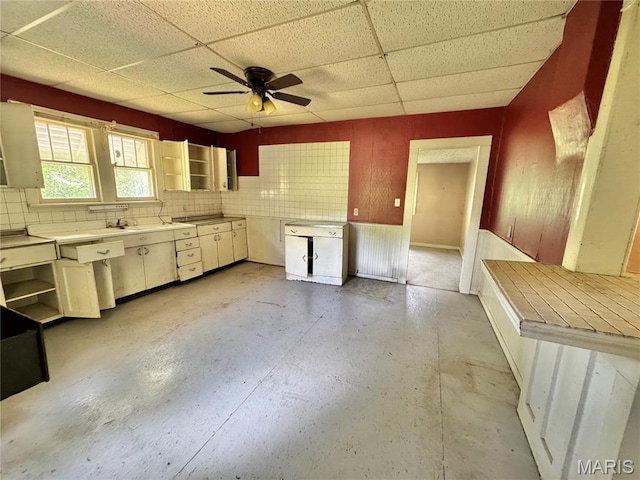 kitchen with a paneled ceiling, a ceiling fan, and concrete floors
