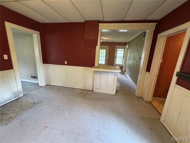 unfurnished room featuring wainscoting, a paneled ceiling, and baseboards