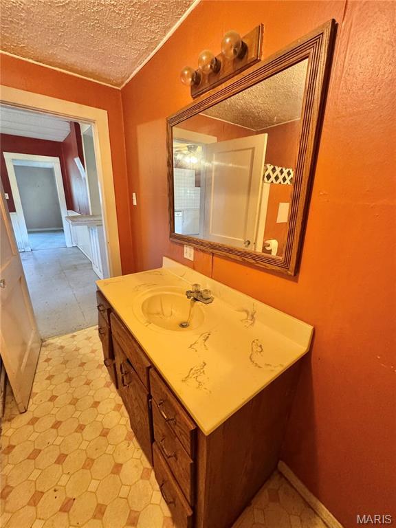 bathroom with a textured ceiling, tile patterned floors, and vanity