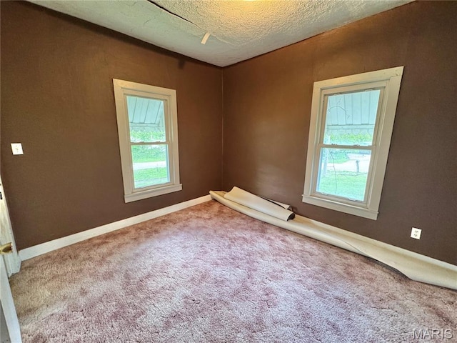carpeted empty room featuring baseboards and a textured ceiling