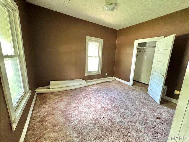 unfurnished bedroom with baseboards, carpet floors, a textured ceiling, and a closet
