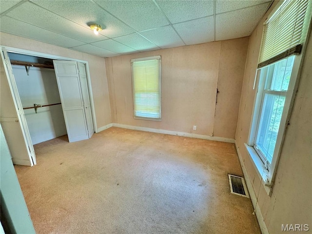 unfurnished bedroom with a closet, a drop ceiling, and carpet