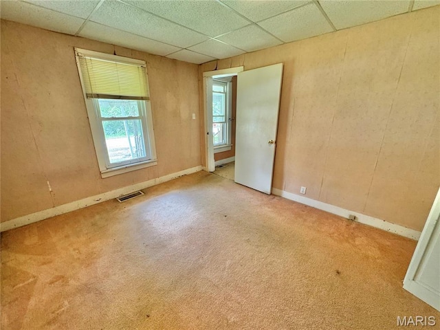 carpeted empty room with a drop ceiling and baseboards