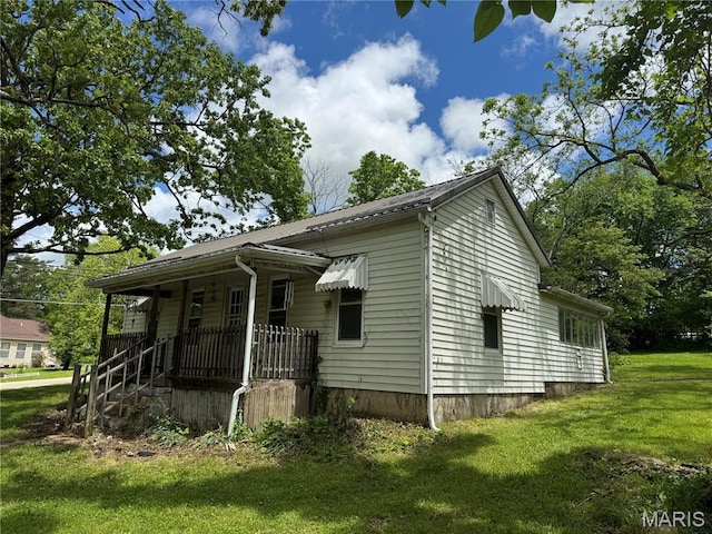 view of side of property with covered porch and a lawn