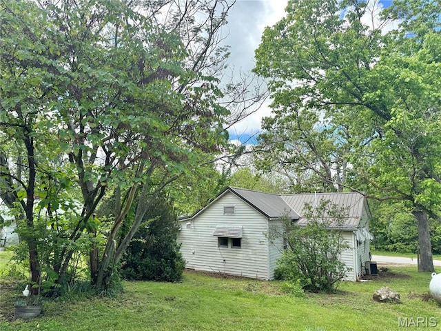 view of side of home with a lawn, central AC, and metal roof