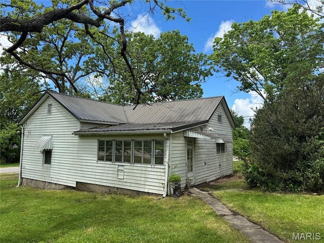 view of side of home with a yard and metal roof