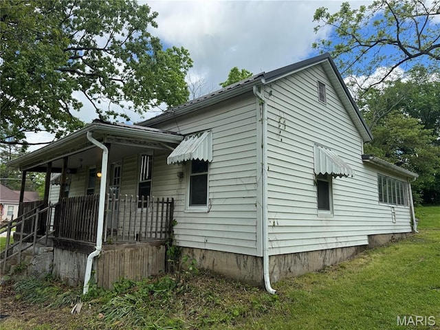 view of side of home featuring a porch and a yard