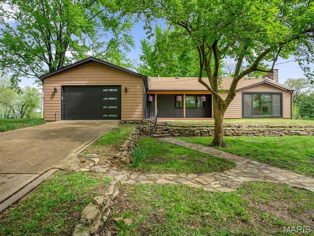 view of front of house with an attached garage, driveway, a chimney, and a front yard