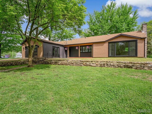 rear view of house featuring a chimney, a lawn, and an attached garage
